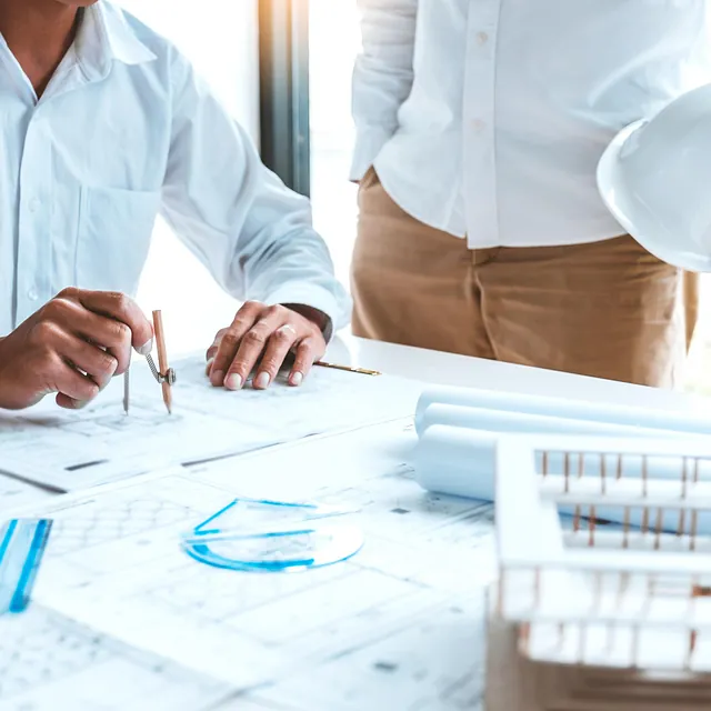 To personer med plantegninger og modell av hus