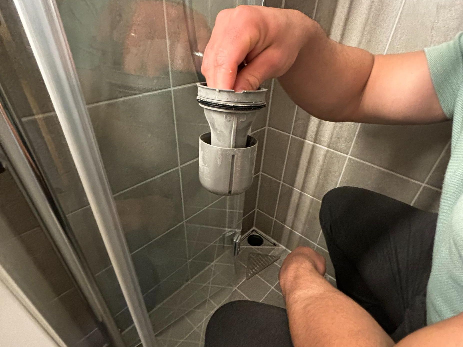 Man holder filter fra dusjgulv i hånden